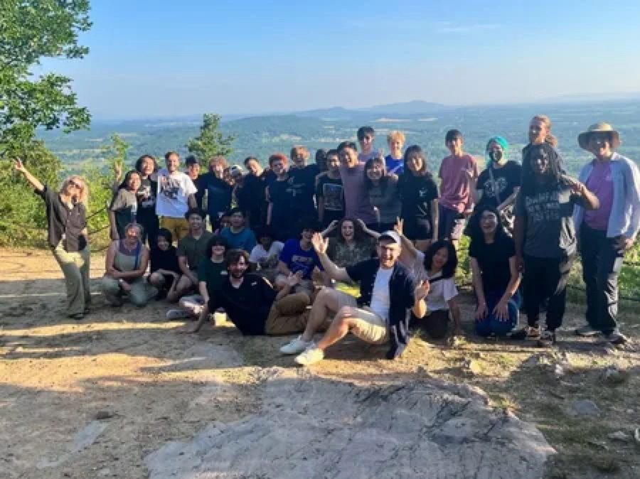 A big group of Hack Clubbers waving on a hilltop at sunset