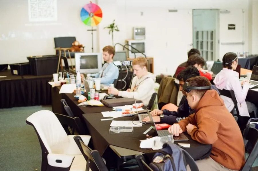 Teenagers coding side by side at long tables during a Hack Club event